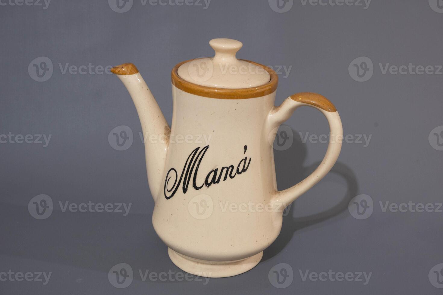 Ceramic teapot of cream colour and glass mug, unique design, kitchen utencil, isolated on grey background photo