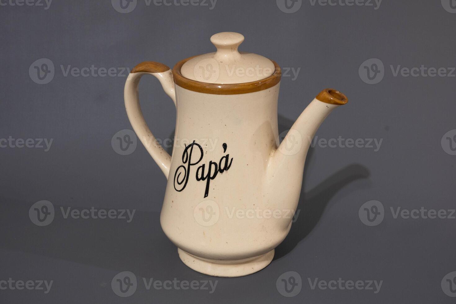 Ceramic teapot of cream colour and glass mug, unique design, kitchen utencil, isolated on grey background photo