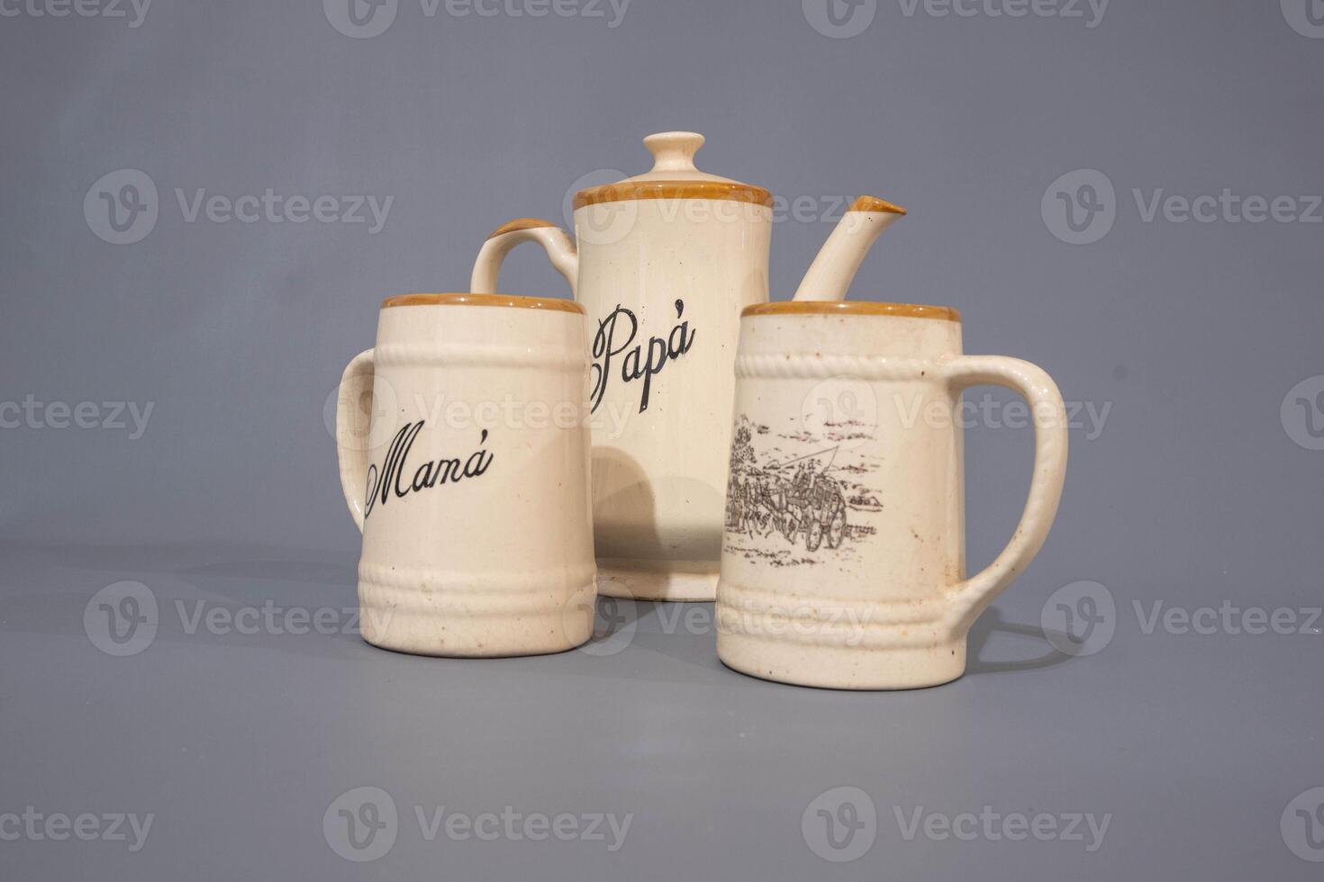 Ceramic teapot of cream colour and glass mug, unique design, kitchen utencil, isolated on grey background photo