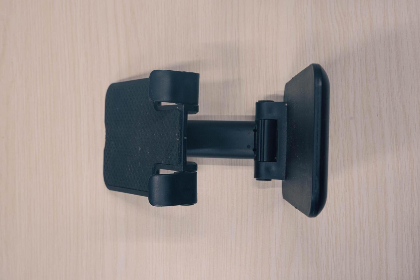 Black cell phone stand shot from the side of high engel. portable cell phone holder on wood textured background photo