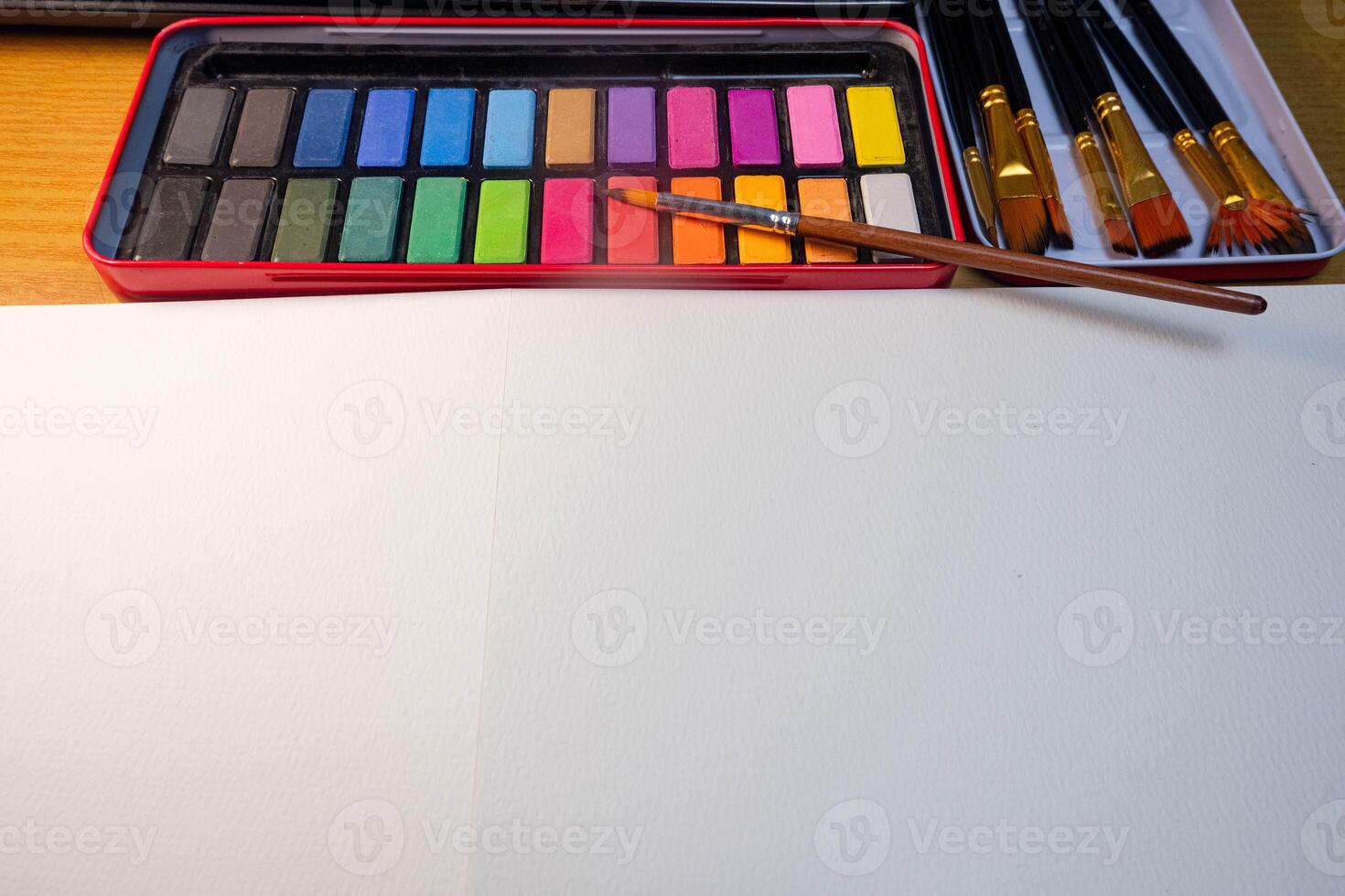Blank drawing book and watercolor color palette. Paint accessories, watercolor and blank book on wooden table. Flat lay, top view. Place for text photo