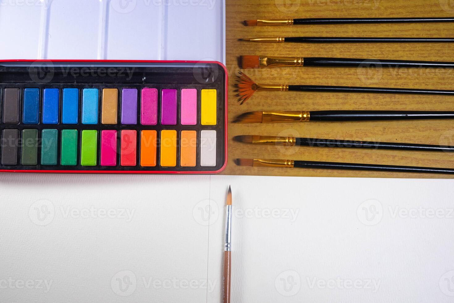 Blank drawing book and watercolor color palette. Paint accessories, watercolor and blank book on wooden table. Flat lay, top view. Place for text photo