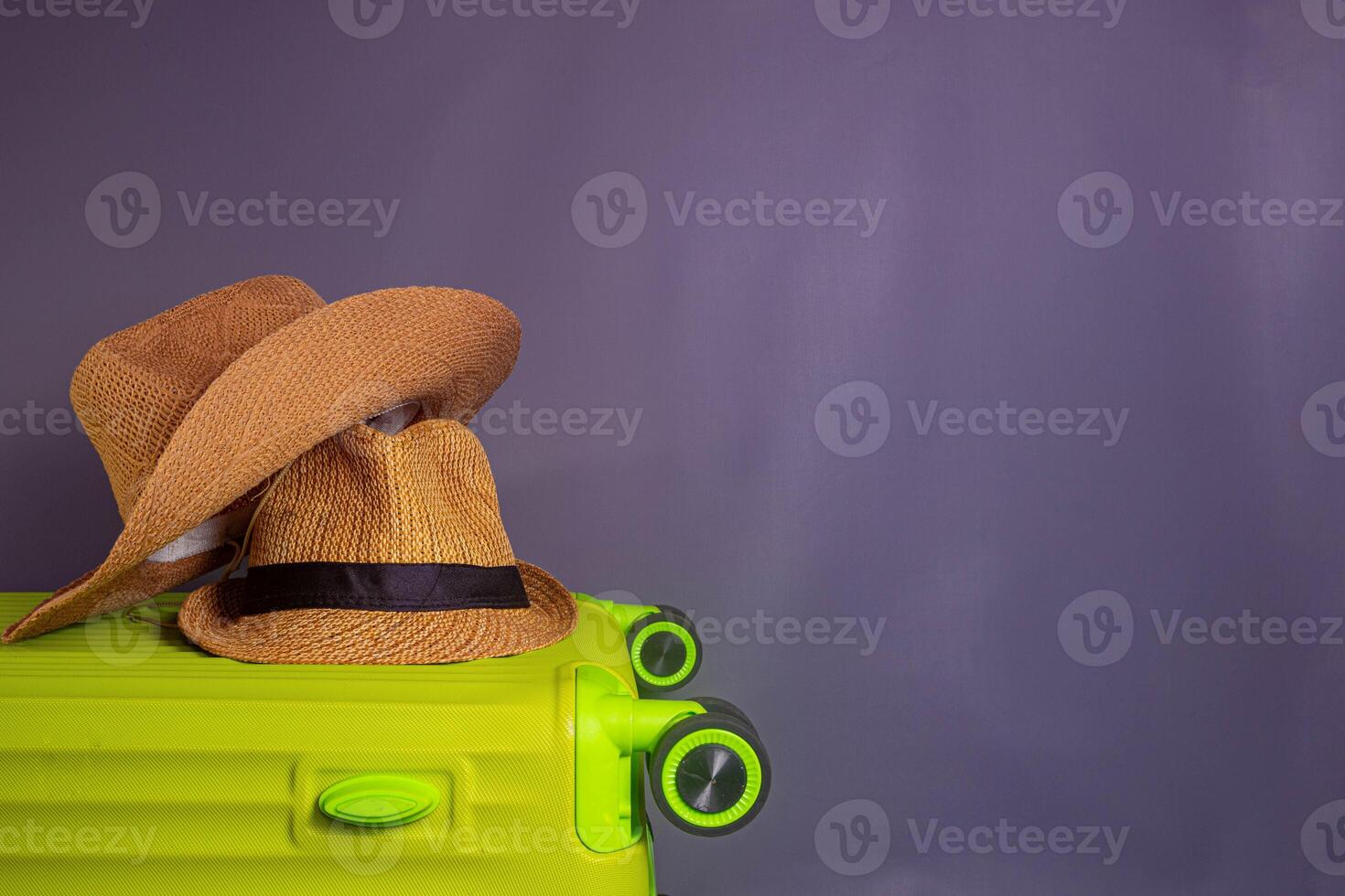 Tourist stuff. Straw hat, shoes, and green suitcase on grey background. Travel item. photo