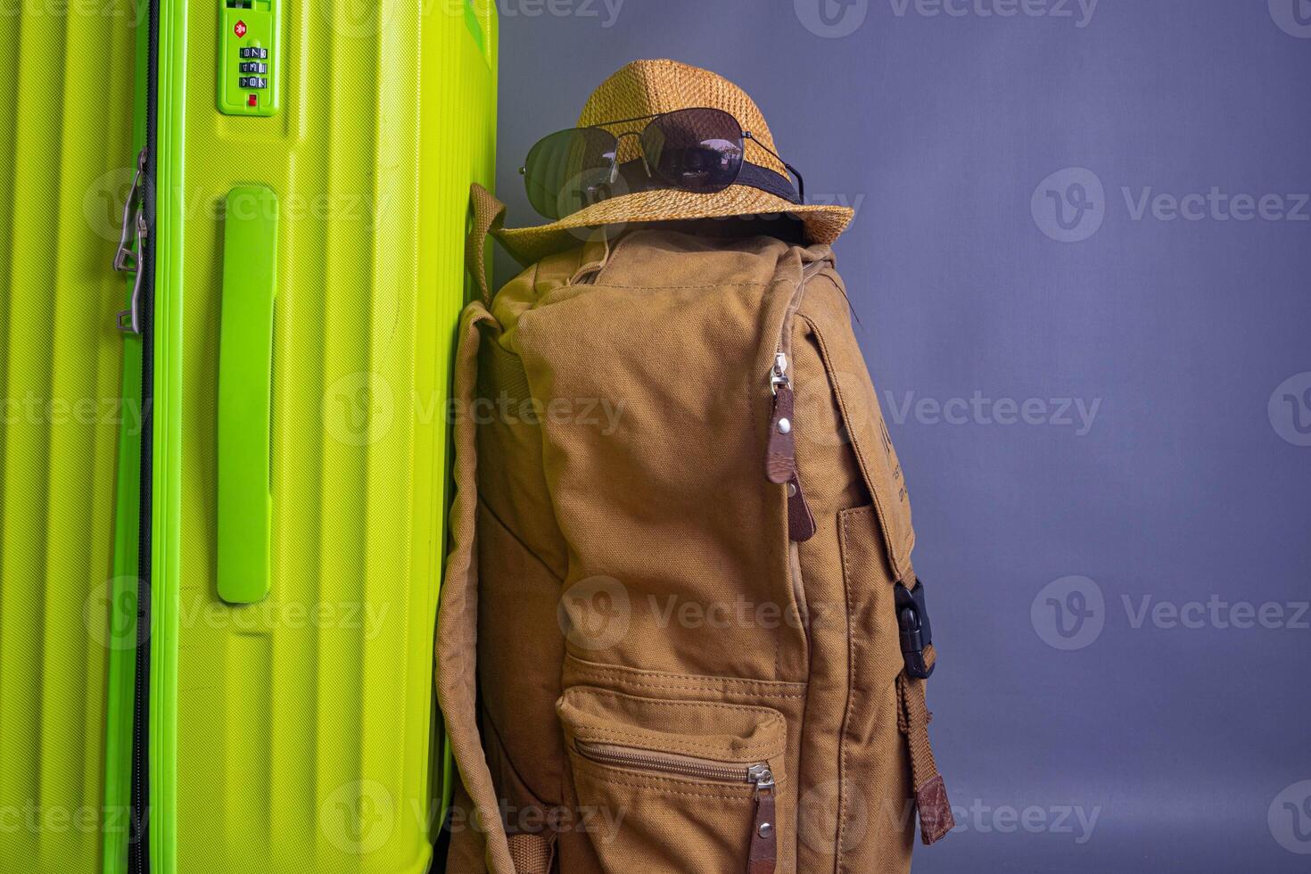Tourist stuff. Straw hat, shoes, and green suitcase on grey background. Travel item. photo