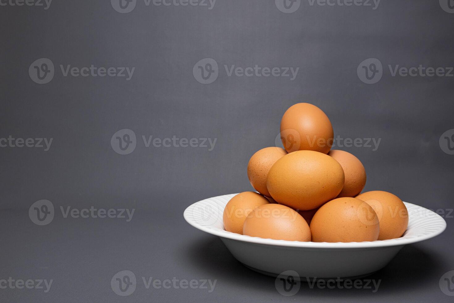 Chicken eggs arranged on a white plate on a black background. photo