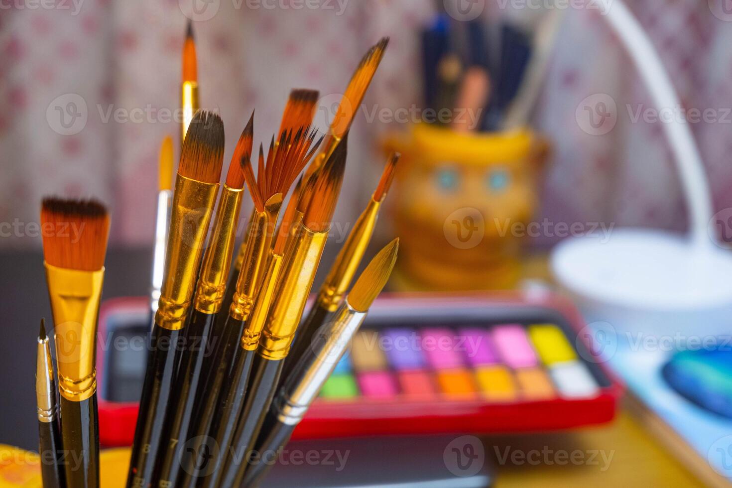 Artistic equipment. Painting brushes with a watercolor color palette background. Paint brushes, watercolor color palette on work table. A set of brushes photo