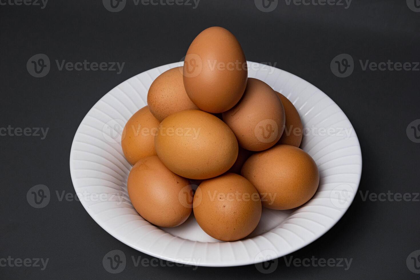 Chicken eggs arranged on a white plate on a black background. photo