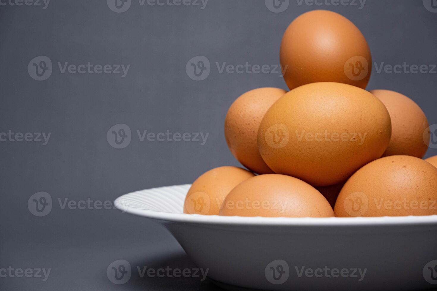 Chicken eggs arranged on a white plate on a black background. photo
