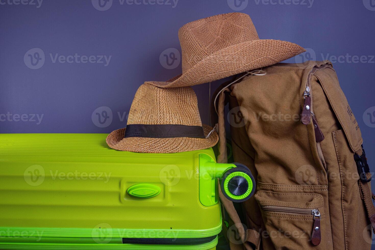 Tourist stuff. Straw hat, shoes, and green suitcase on grey background. Travel item. photo