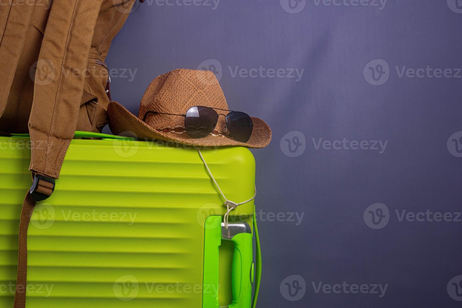 Tourist stuff. Straw hat, shoes, and green suitcase on grey background. Travel item. photo