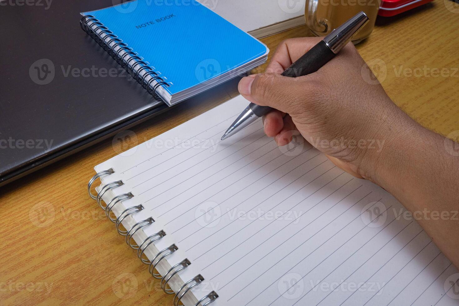 Hands holding pencils and notebooks. Hand with a pen is writing in a notebook. Mock-up Concept. photo
