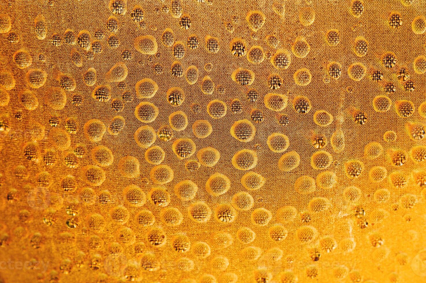 Drops of golden honey hang from the fabric in shallow depth of field. Concept of honey production and background for honey drinking culture photo