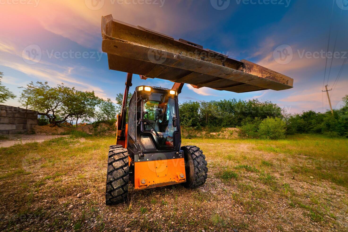 loader clears a construction site. Land works for landscaping. A machine for work. A small tractor with a bucket for moving soil, turf and bulk materials photo