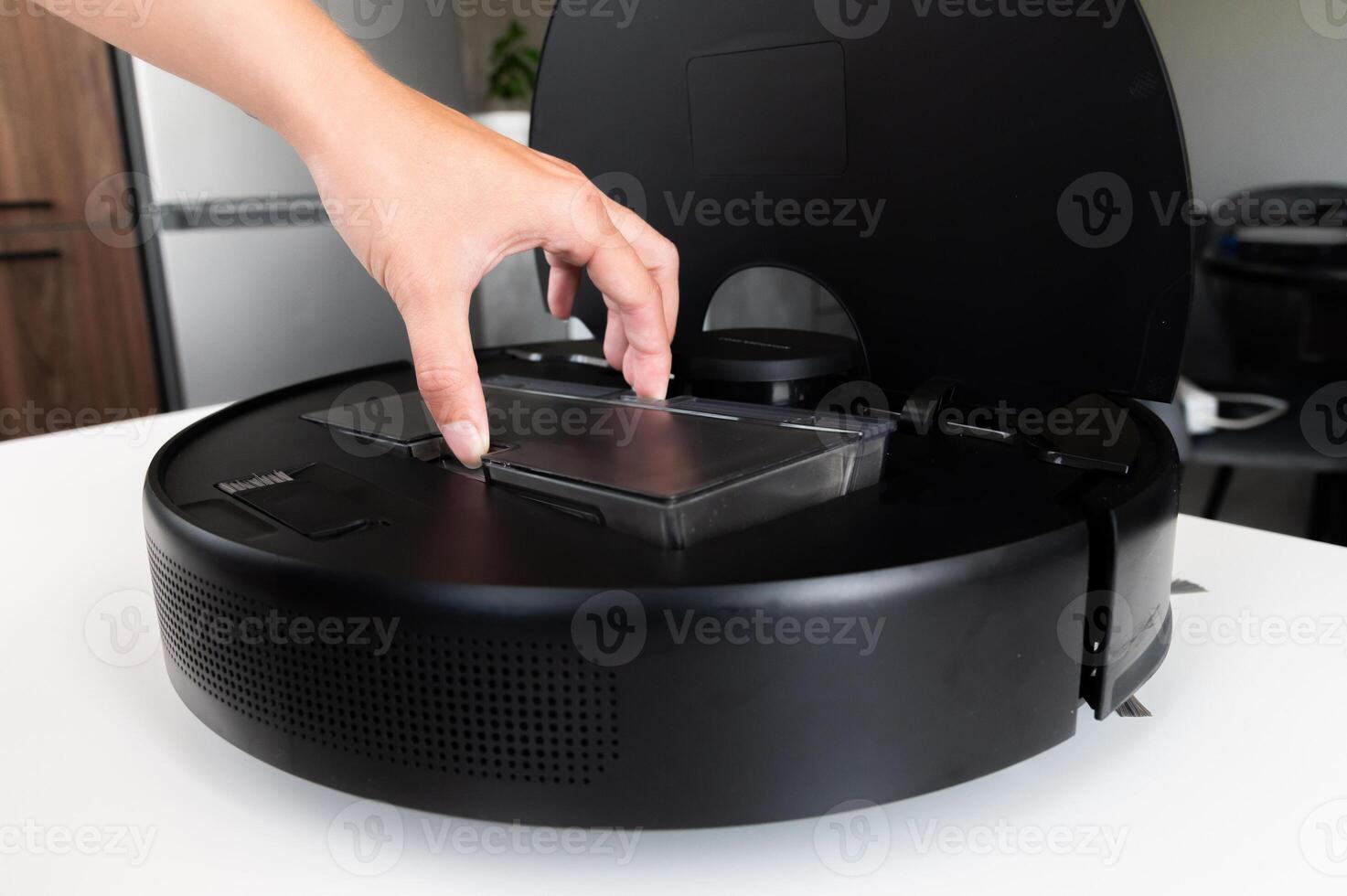The hands of a Caucasian young woman are cleaned by a robot vacuum cleaner. An overturned vacuum cleaner on the table. Service photo