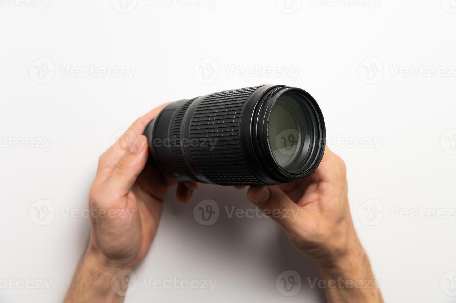 Horizontal shot of a camera lens on the hands of a man holding a zoom telephoto lens photo