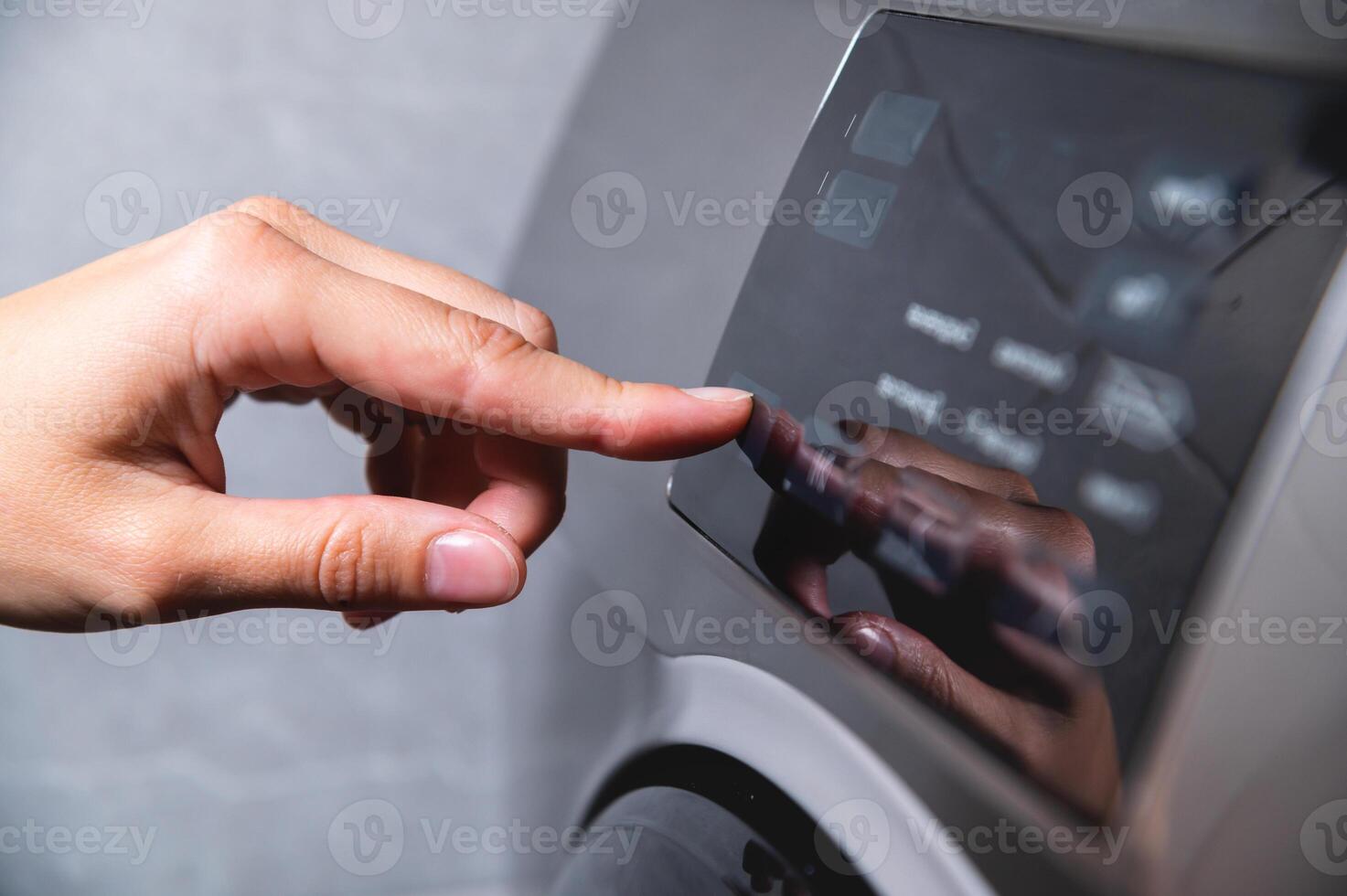 close up view of a washing machine set to low temperature wash cyle to reduce cost and energy to clean laundry, persons hand shown about to press the start button photo