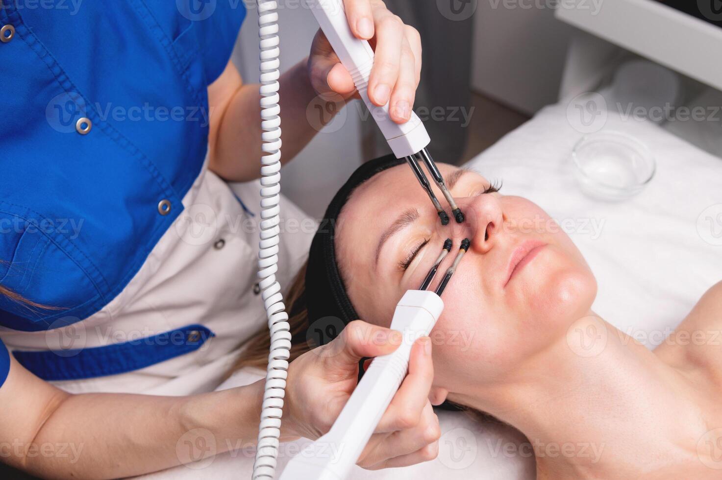 Ultrasonic facial treatment on ultrasound face machine. Woman taking electric lift massage spa salon. Stimulation muscles on professional equipment microcurrent therapy. New methods of rejuvenation photo