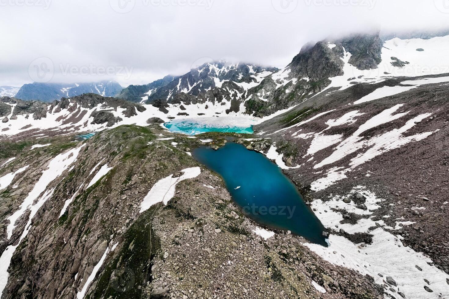 Aerial view of three frozen mountain lakes, shot with a drone at a wide angle. Icy cloudy day in the snowy mountains, in the wilderness photo