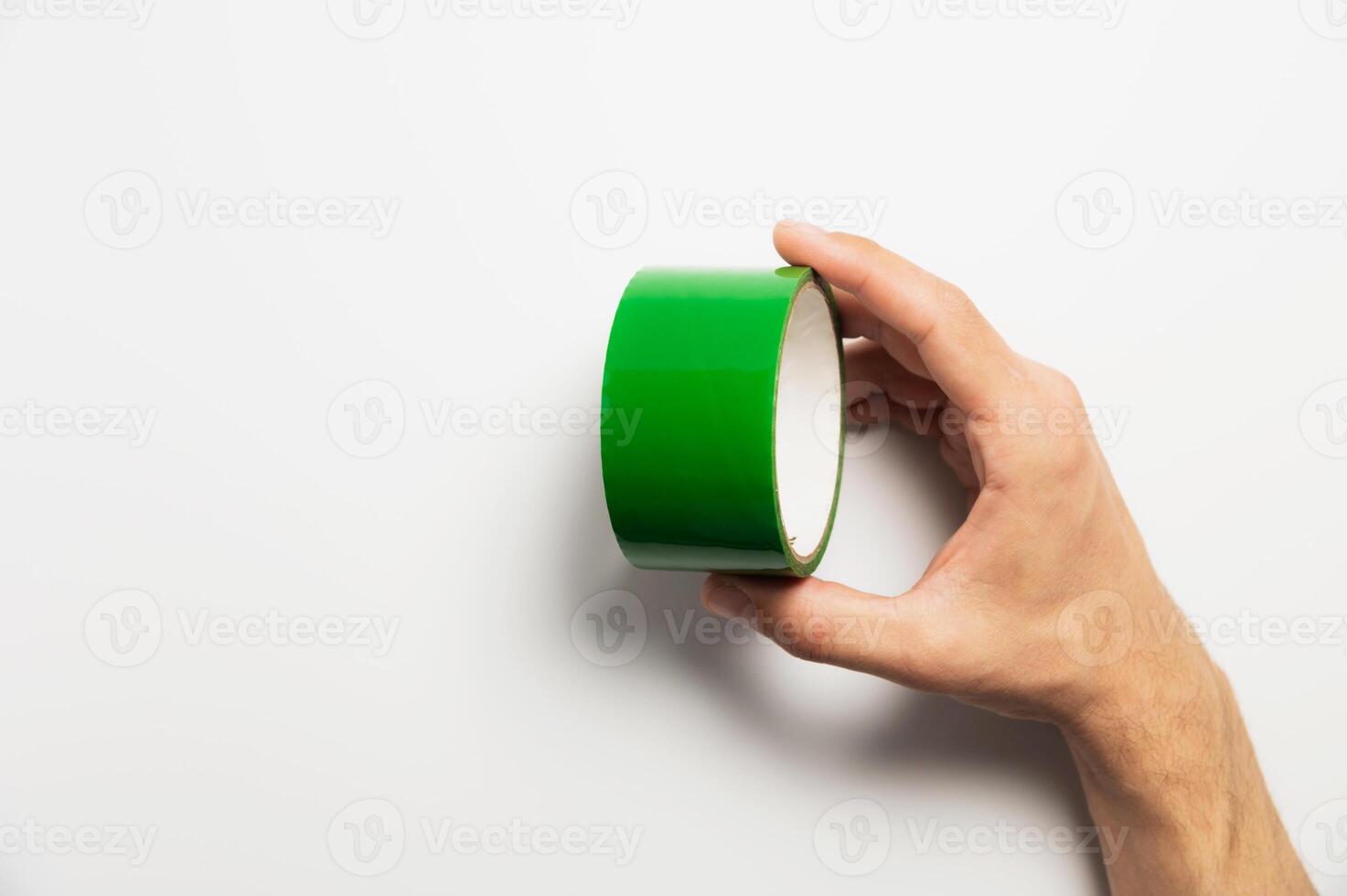 Roll of adhesive black reinforced tape lies on the palm of a worker on a white background, close-up of a hand photo