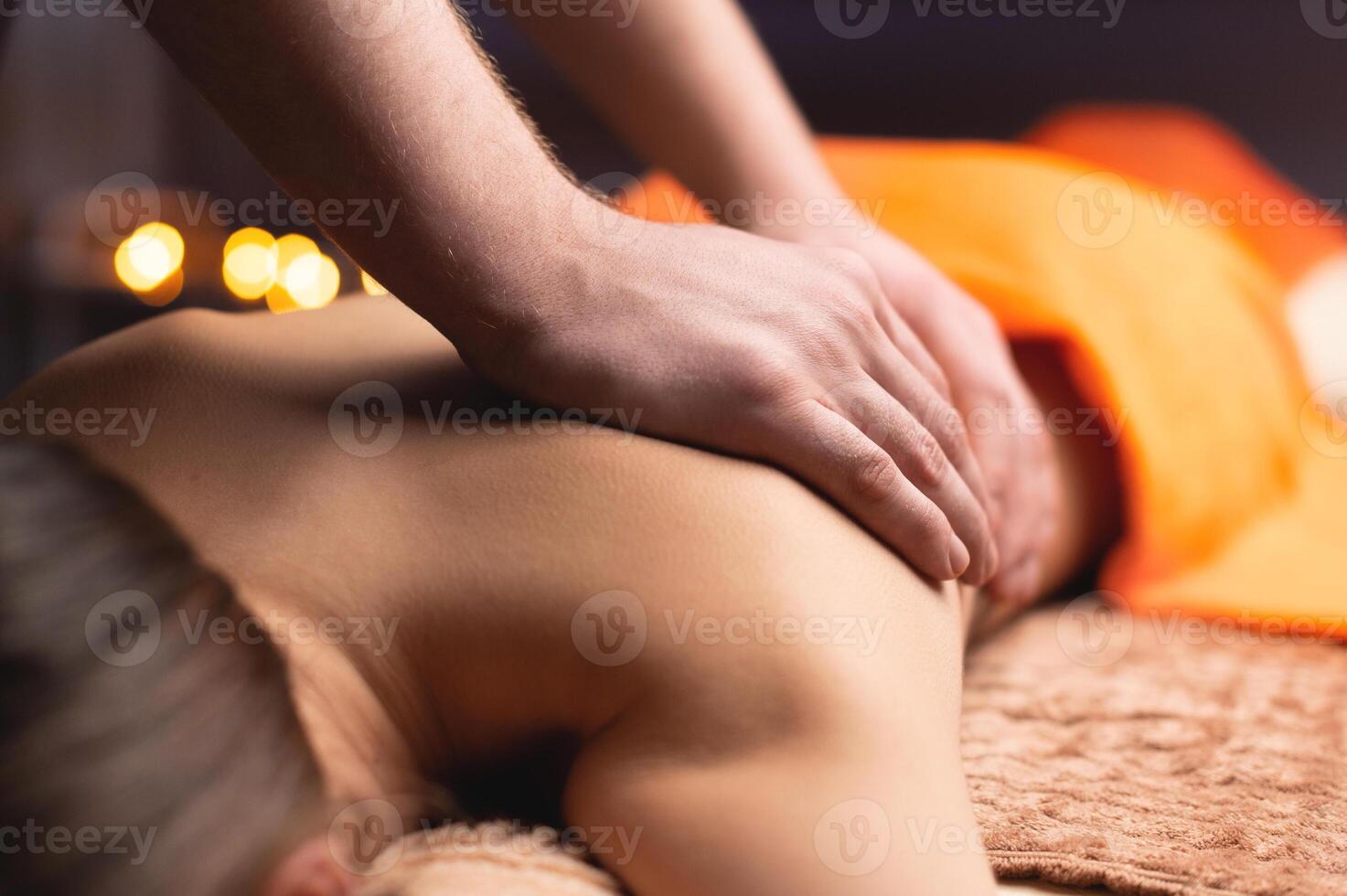 Masseur massaging back close-up. Candlelight setting, spa salon, relaxing day off photo