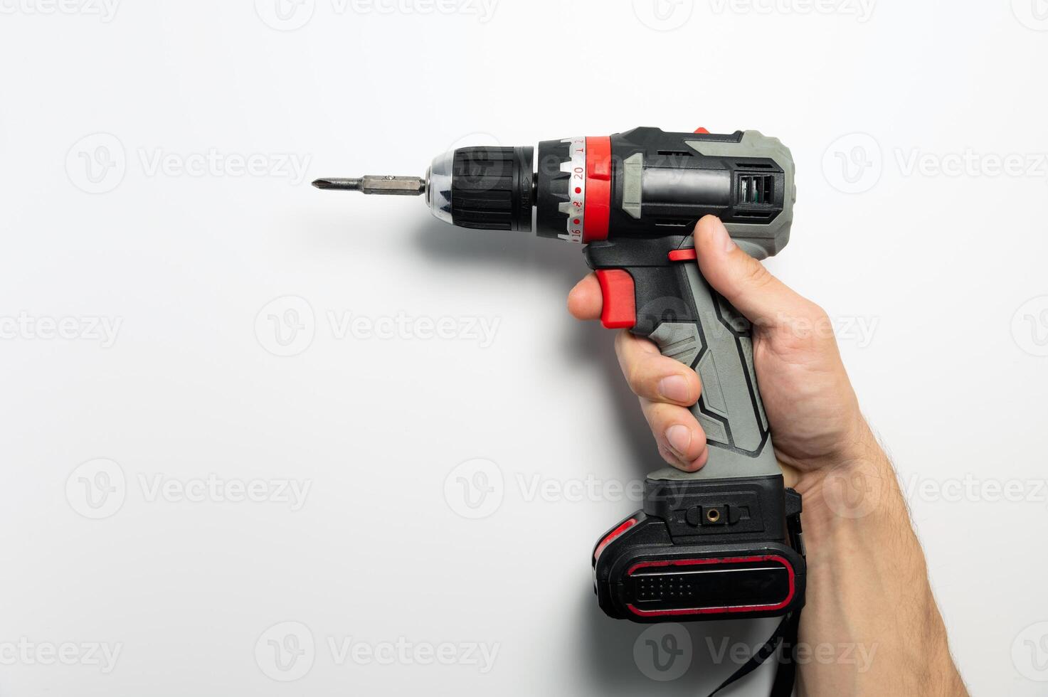 Cordless screwdriver in male hand on white background. Close-up of working tool, household help at hand photo