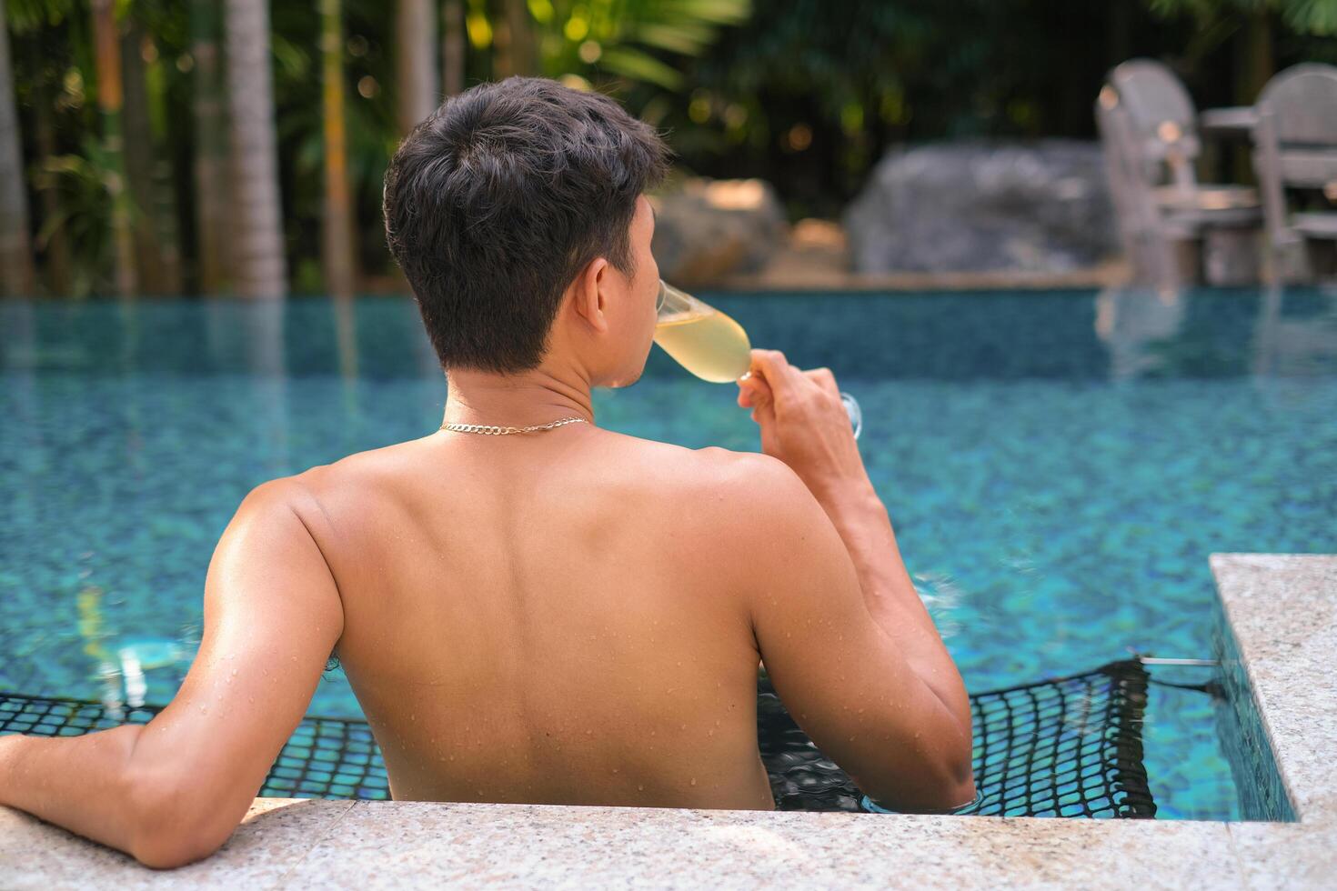 A man has a rest in the pool and enjoying glass of tasty cold white wine during vacation. Travel vacation. Summer holidays. photo