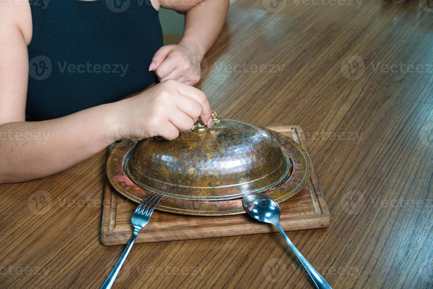 Woman Opening a Copper Dish at a Table photo
