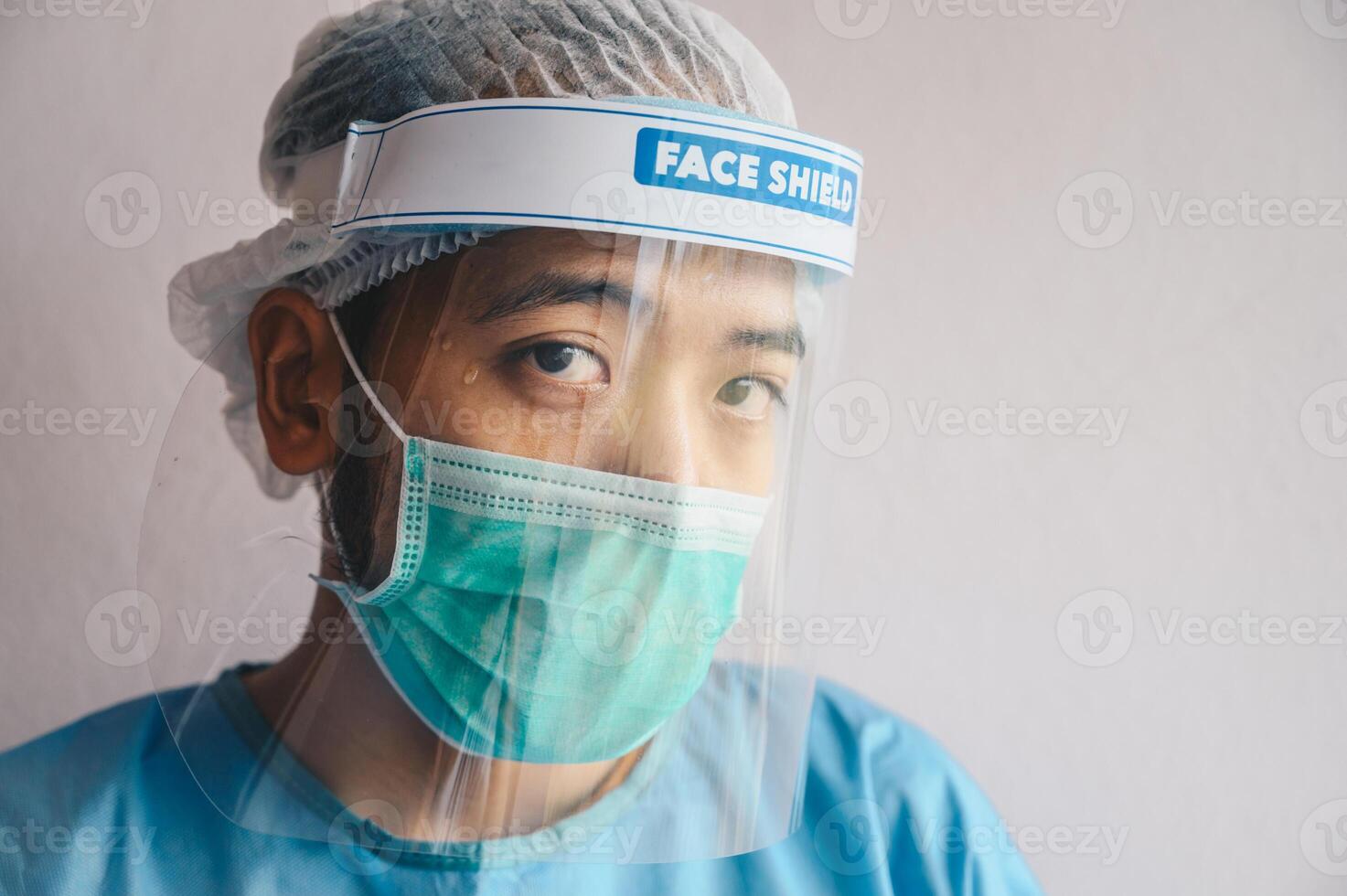 Portrait of Doctor having tired from work while wearing PPE suit for protect coronavirus disease. The wellbeing and emotional resilience are key components of maintaining essential care services. photo