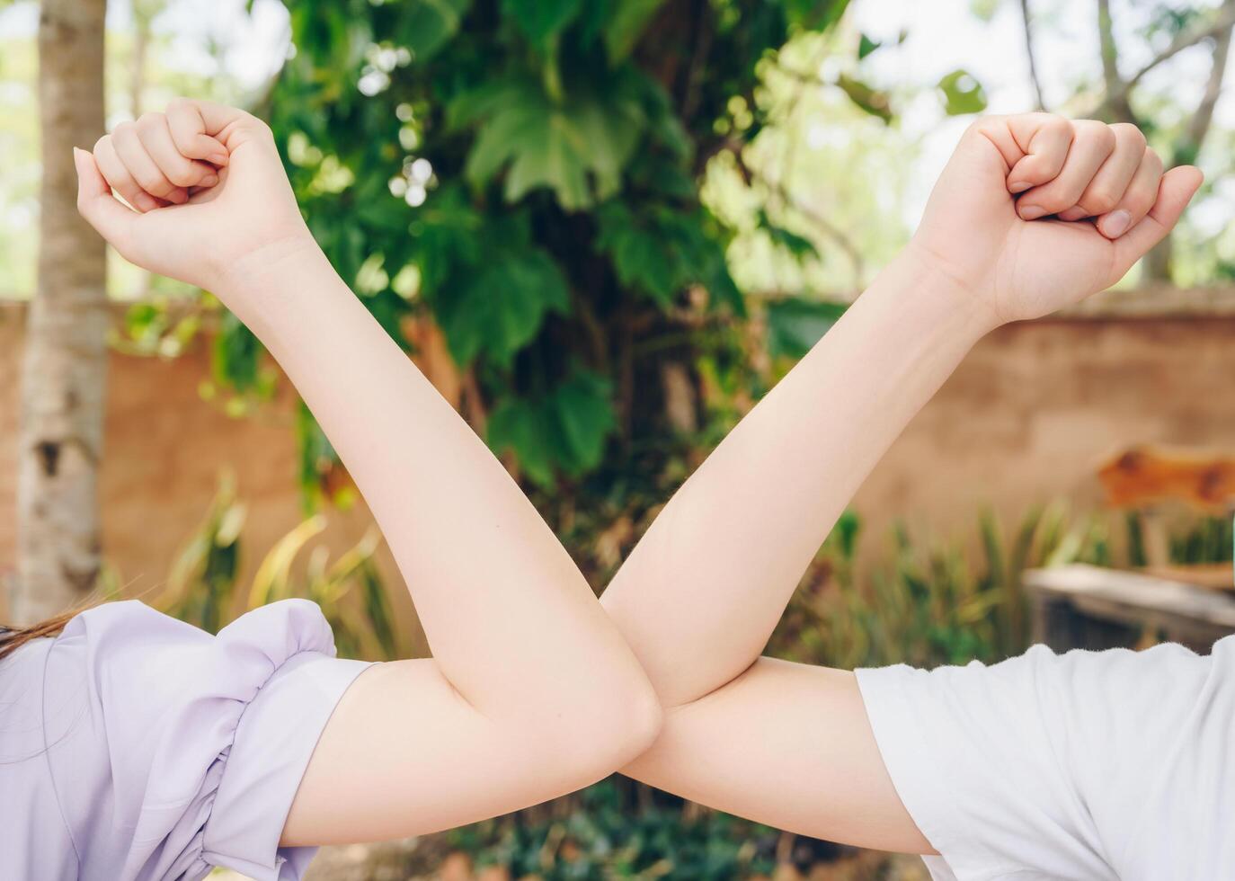 Cropped shot of two women bump elbows for greeting during coronavirus epidemic. The elbow bump was suggested as an alternative way for reduce your risk of spreading or contracting the virus. photo