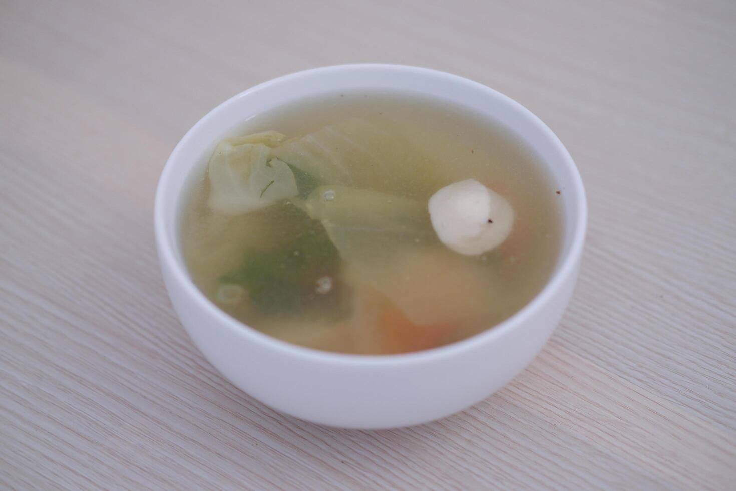 A bowl of soup on a wooden table photo