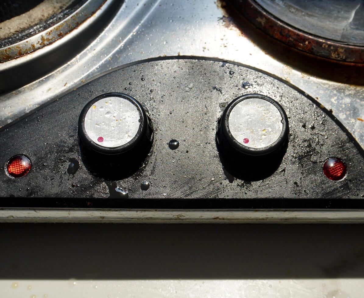 Unclean oily old kitchen stove switches isolated on horizontal ratio white counter background. photo