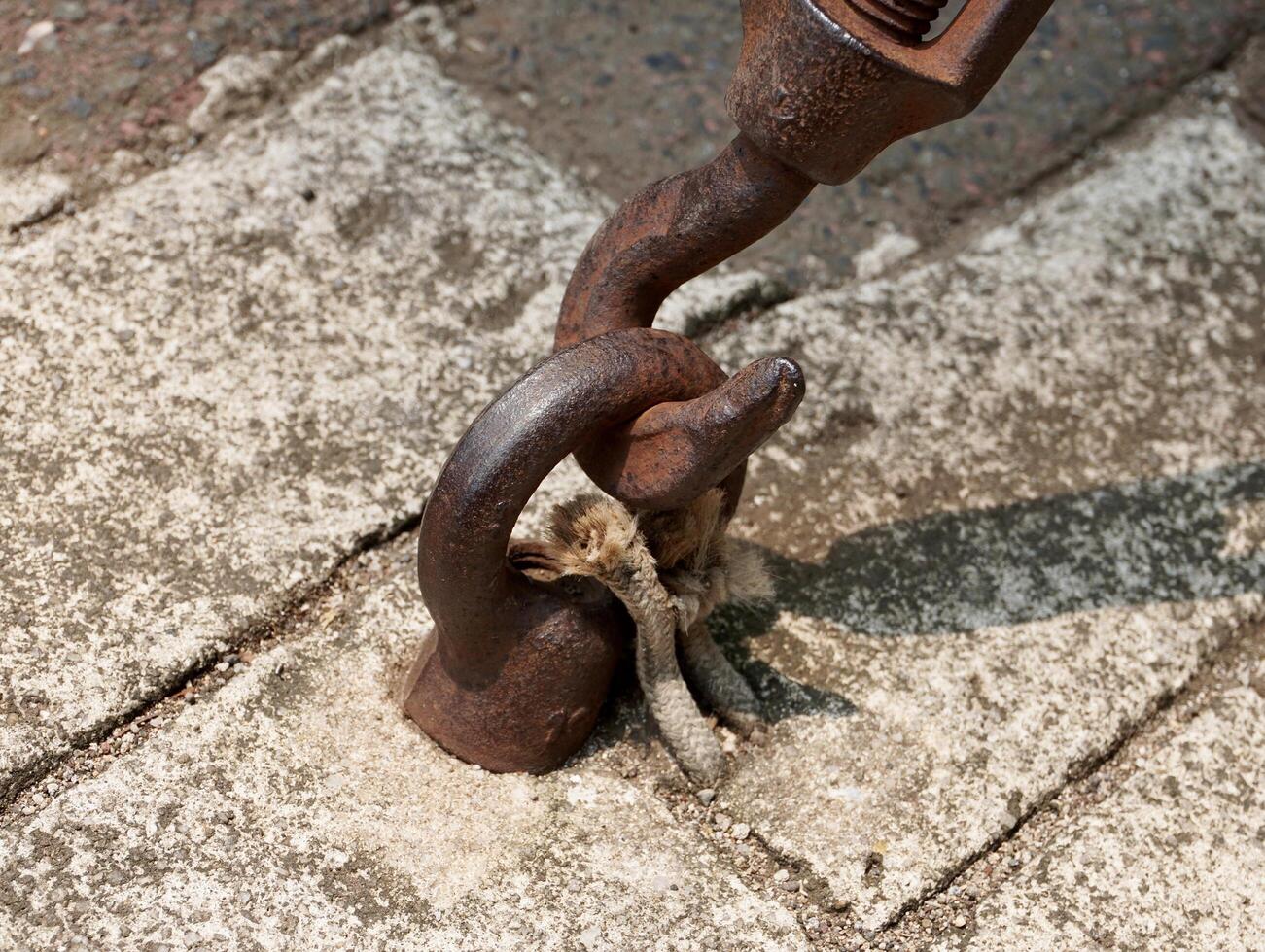 Industrial heavy duty old and rusty hook connector object isolated on horizontal ratio outdoor ground gray brick flooring environment background. photo