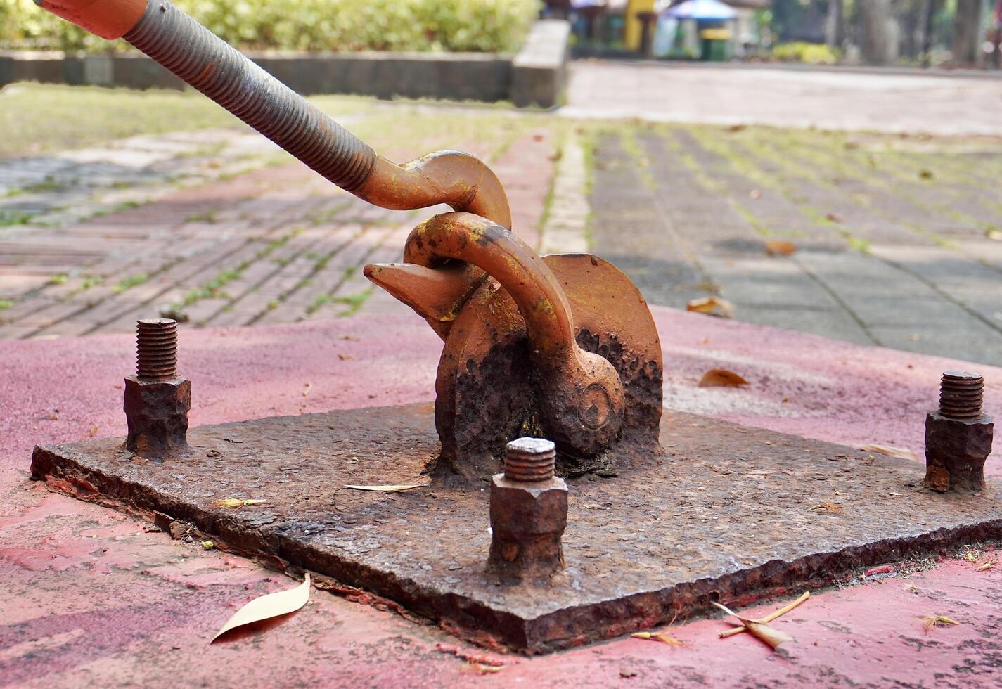 Industrial heavy duty old and rusty orange painted hook connector object isolated on horizontal ratio outdoor ground flooring environment background. photo
