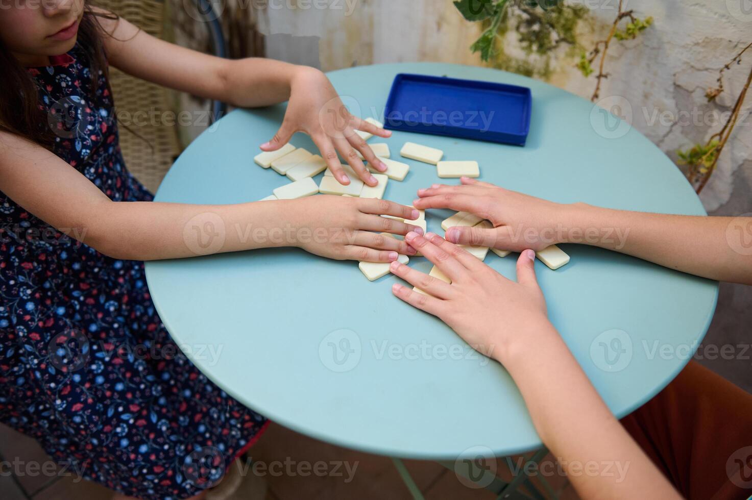 Children playing a fun game of dominoes on a round table in an outdoor setting, emphasizing creativity and connection photo