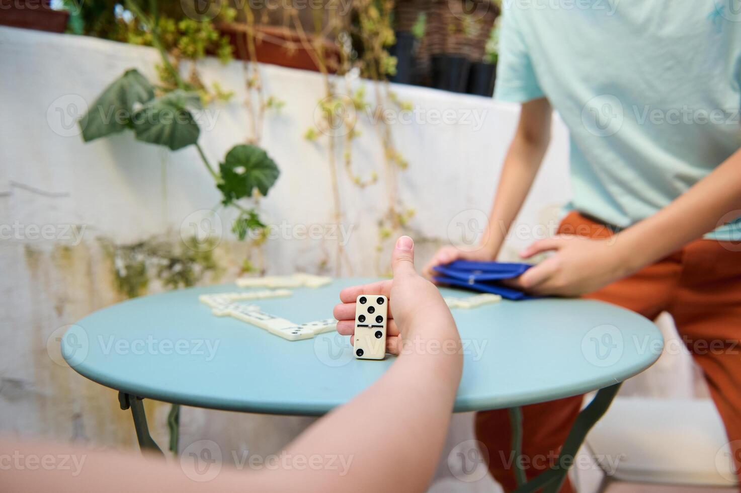 Playing a game of dominoes on a patio with friends, capturing a moment of fun and relaxation, amid lush greenery and a serene atmosphere. photo