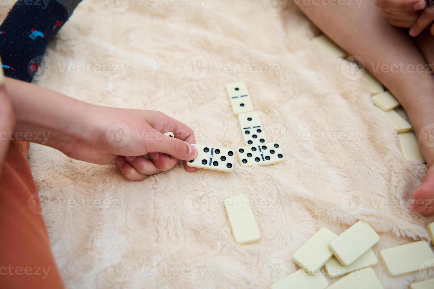 People playing dominoes on a soft blanket, focusing on hands and gameplay pieces, capturing a cozy and engaging pastime activity with a warm, relaxed atmosphere. photo