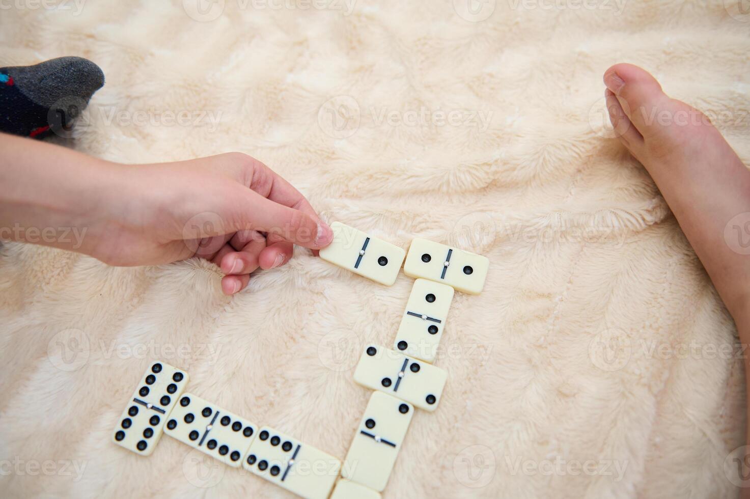 Child and adult play domino game on soft plush blanket creating a cozy and relaxing atmosphere for family bonding photo