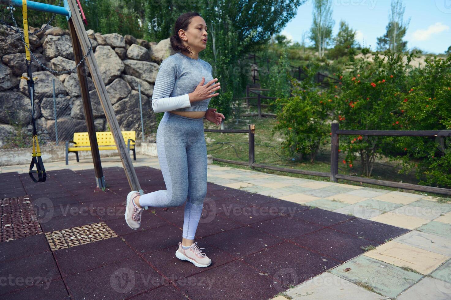 Woman exercising outdoors in a park setting, wearing athletic wear, performing a warm-up routine in a serene natural environment, demonstrating fitness and healthy lifestyle habits. photo