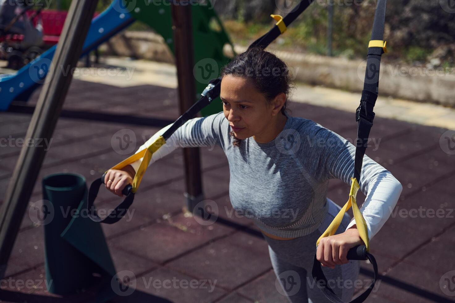 Outdoor fitness training with woman using suspension straps for strength exercise at a park on a sunny day photo