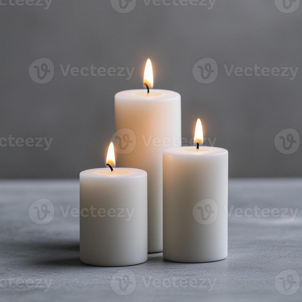 Pillar candles burning against a smooth gray background in a minimalist setting photo