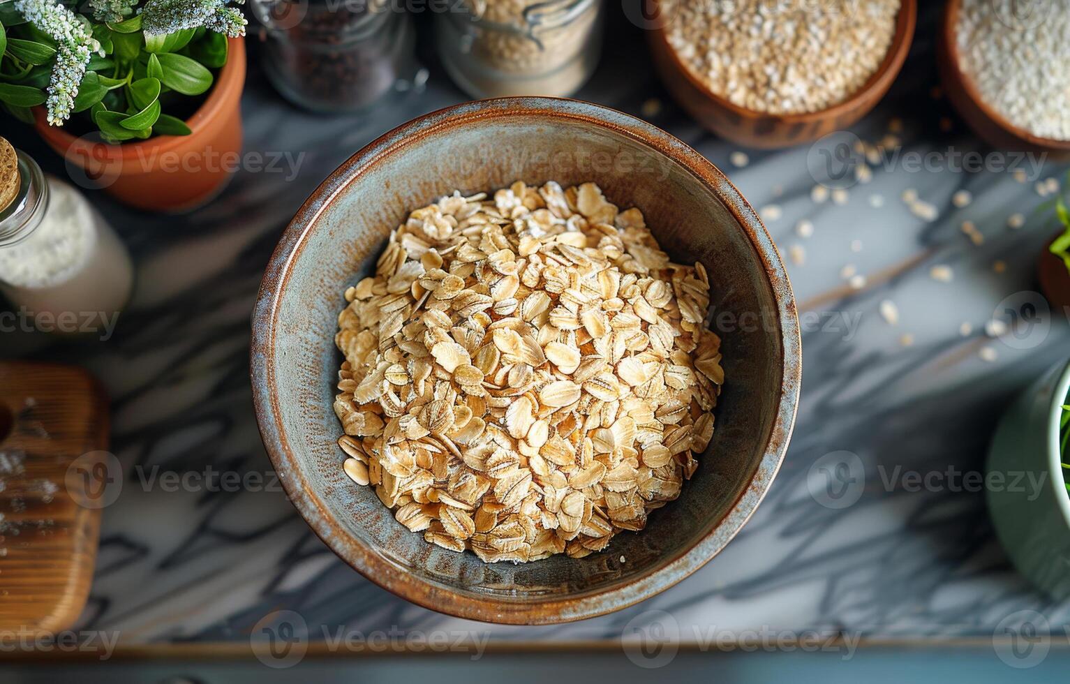 A bowl of oatmeal sits on a marble countertop. The bowl is filled with oatmeal and is surrounded by various kitchen items such as a bottle, a cup, a bowl, and a spoon photo