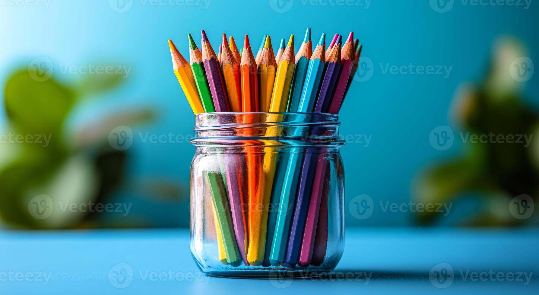 A jar full of colorful pencils on a blue table. The jar is full of pencils of different colors, and the pencils are arranged in a way that they are all visible. Concept of creativity and organization photo