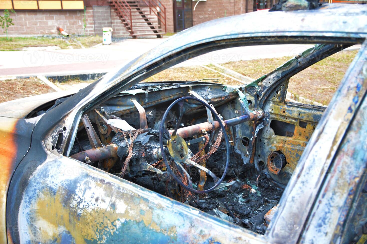 A burned out car with rusted steering wheel. Vehicle fire due to short circuit, bombing. Stolen car intentional arson. A vehicle damaged in the fire. photo