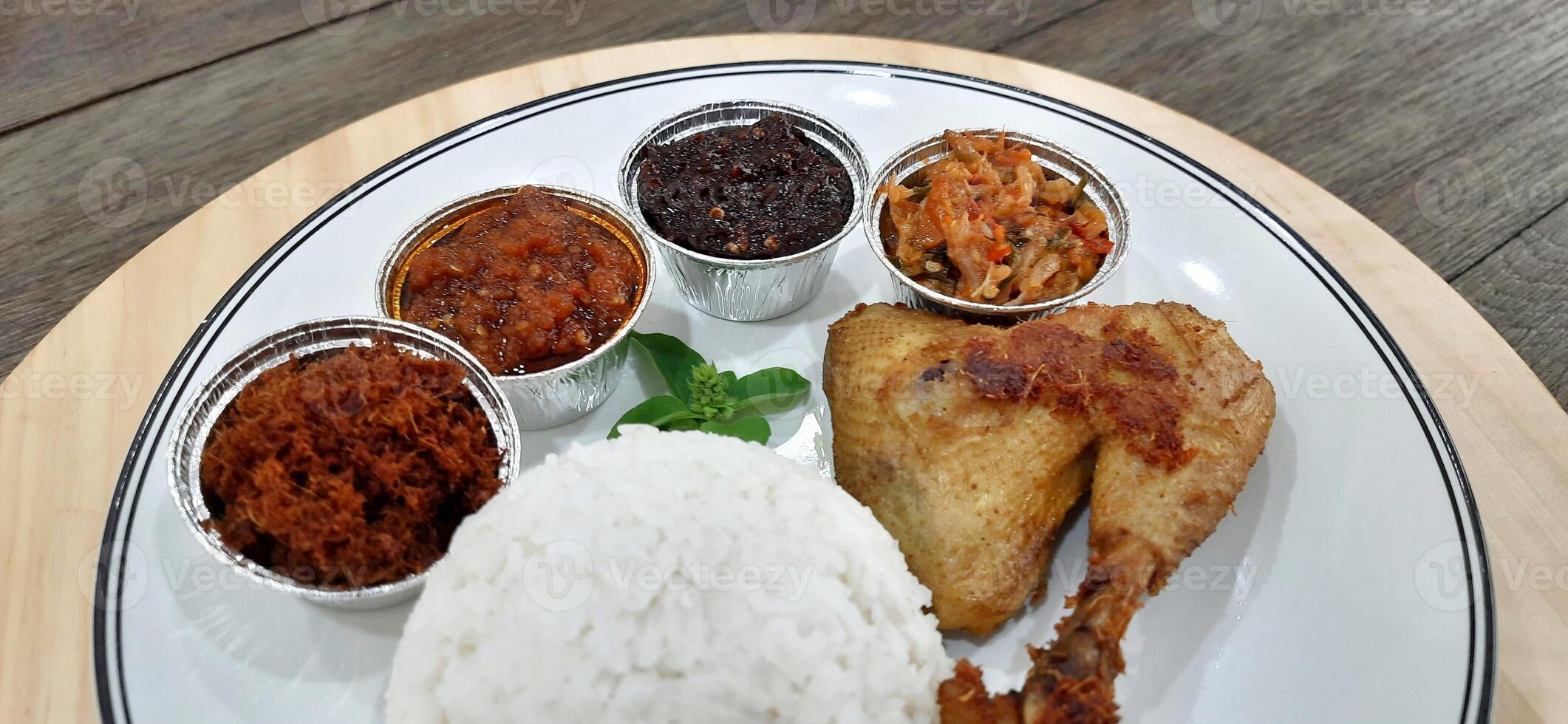 Ayam ungkep bumbu kuning or boiled chicken with curry seasoning and coconut water. Served with varian sambal or hot chili sauce. Ready to fried photo