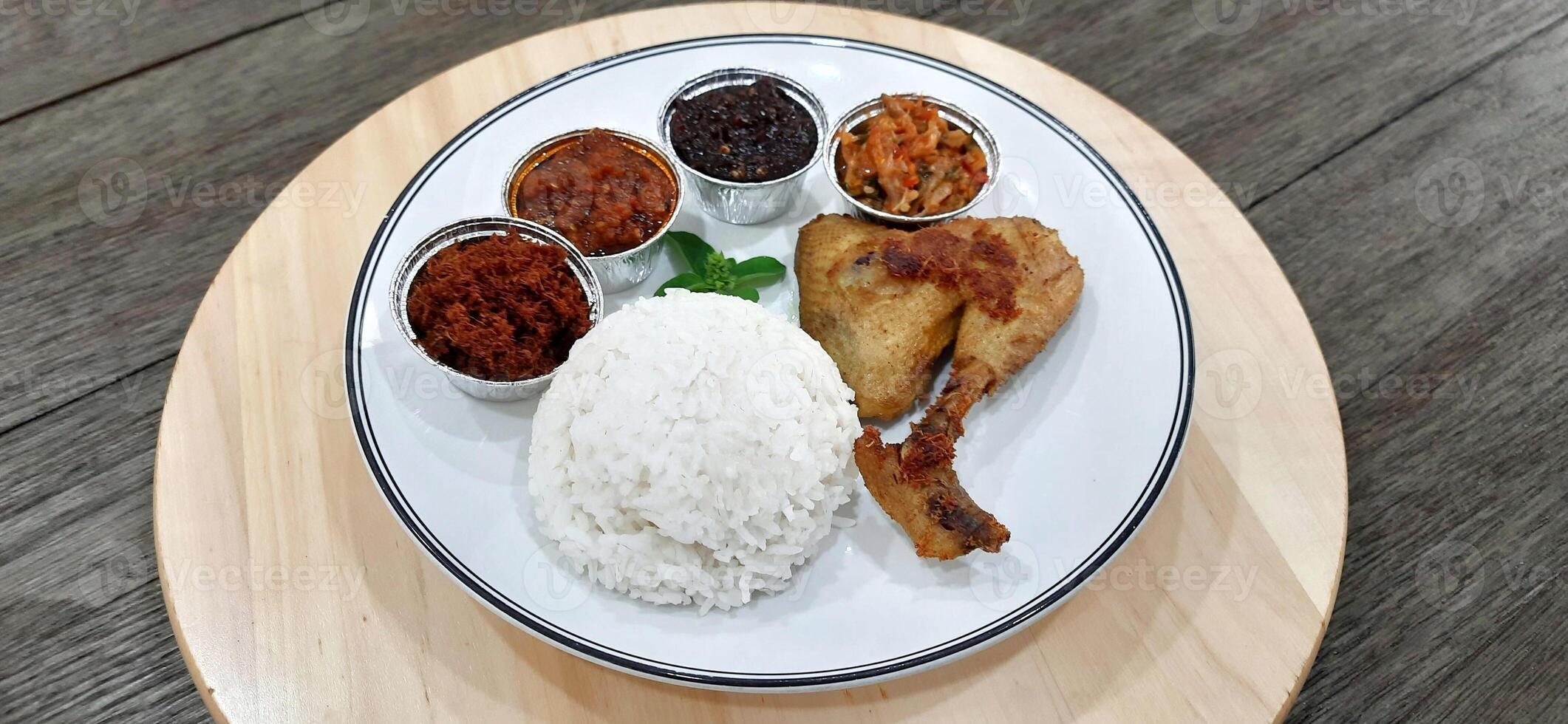 Ayam ungkep bumbu kuning or boiled chicken with curry seasoning and coconut water. Served with varian sambal or hot chili sauce. Ready to fried photo