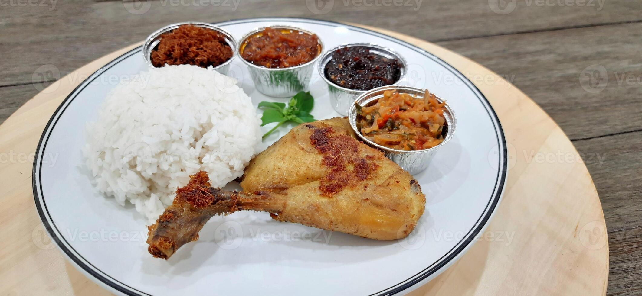 Ayam ungkep bumbu kuning or boiled chicken with curry seasoning and coconut water. Served with varian sambal or hot chili sauce. Ready to fried photo