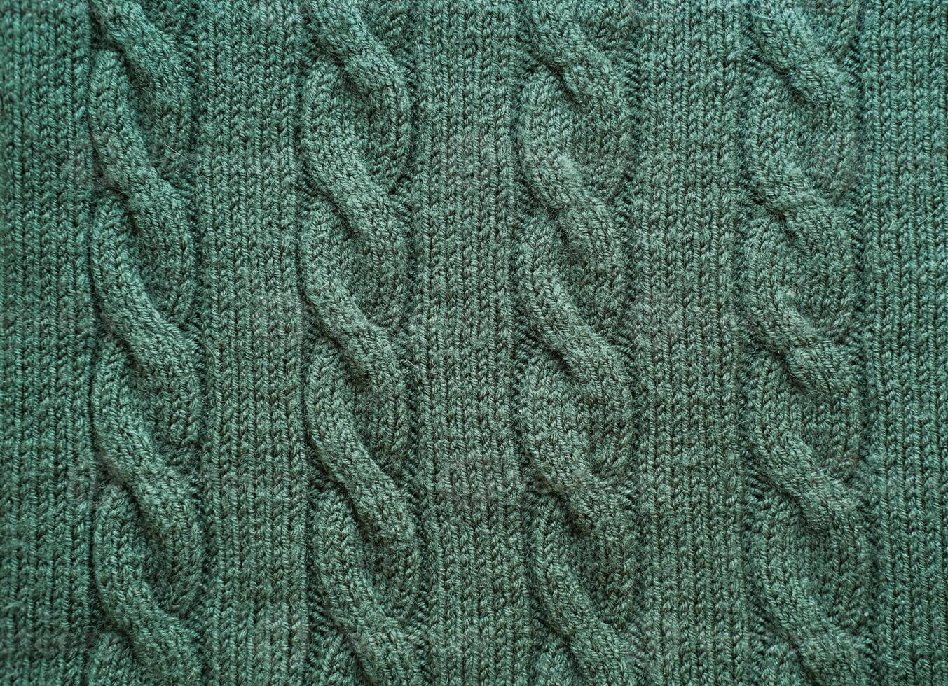 Texture of hand-knitted fabric made of green threads, cables knitting stitch pattern photo