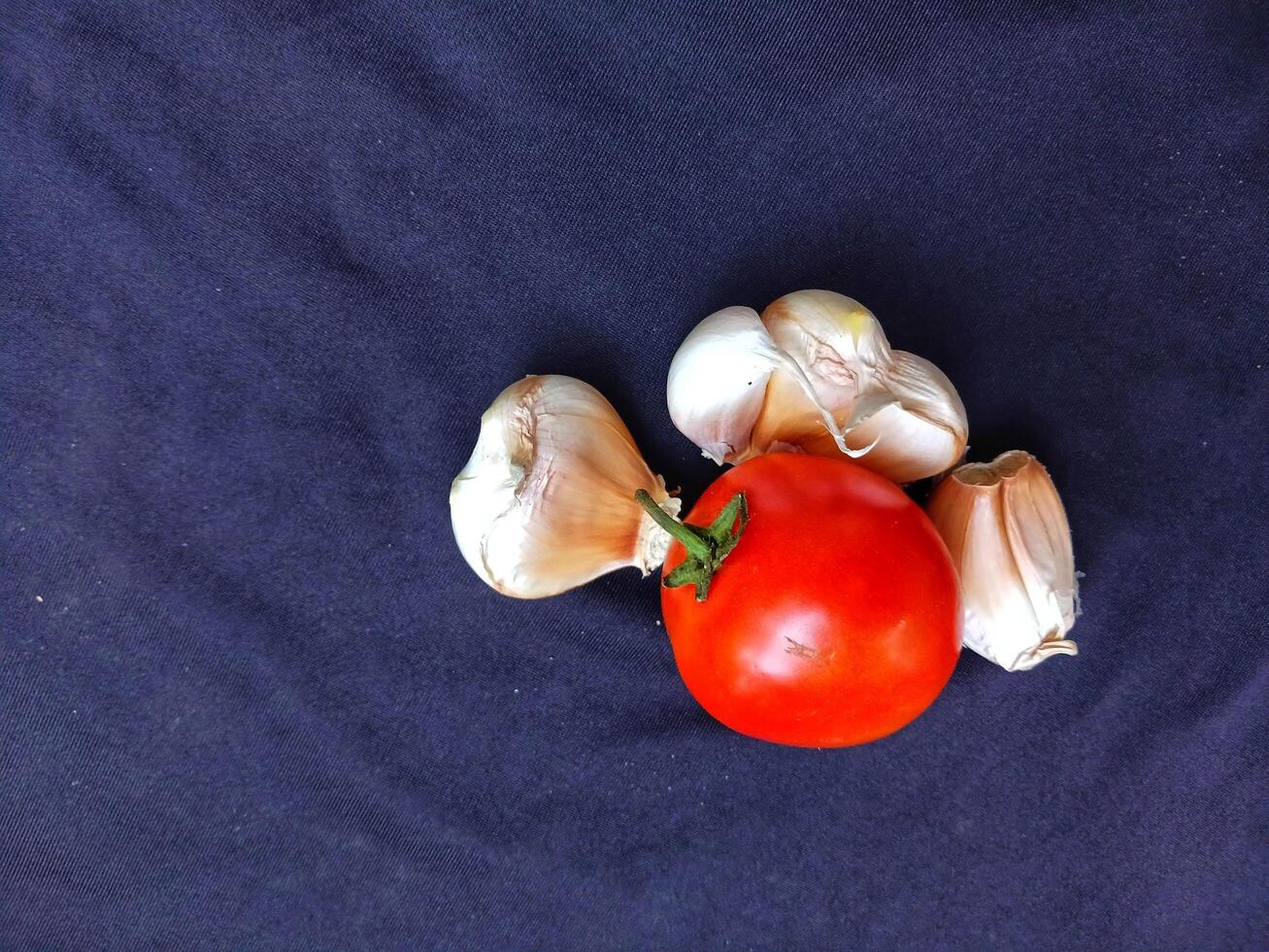 Tomato and garlic vegetable fruit on navy cloth background good for food. photo