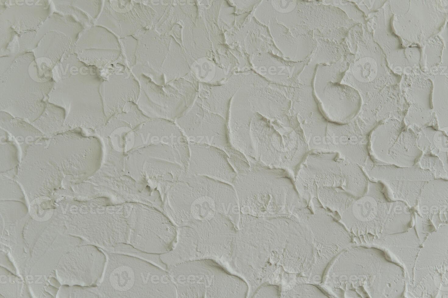 Photography of a wall covered in white paint or cement with a textured, uneven surface. photo