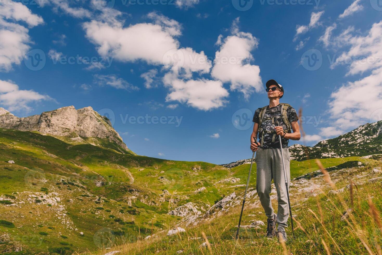 Man Walking with Hiking Poles on Mountains photo